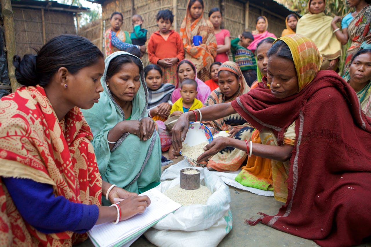 Village women in Bangladesh gather for community development planning and resource distribution.